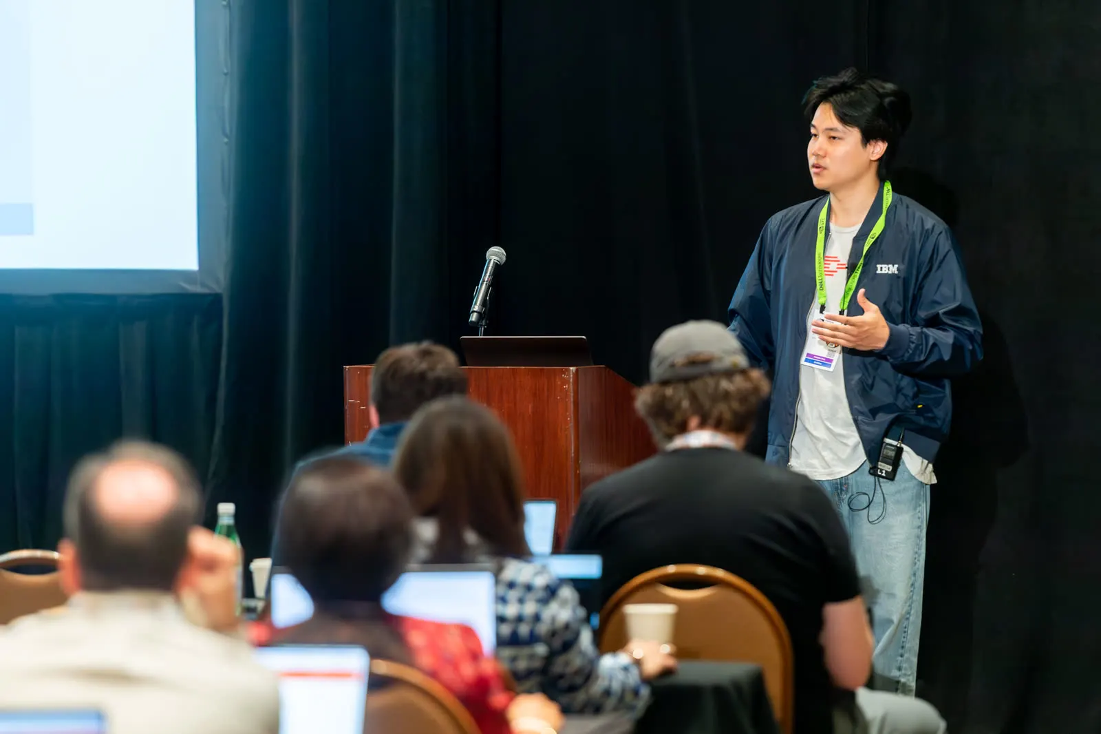 An instructor standing at the front of a workshop at All Things AI 2026, talking with people seated at tables with their laptops open