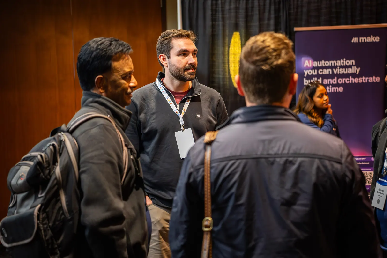 A small group in conversation beside the Make banner at All Things AI 2026