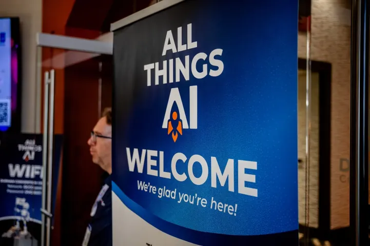 A blue All Things AI banner at the entrance reading WELCOME, we're glad you're here