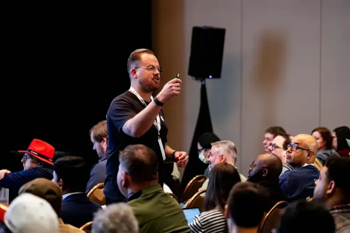 Taylor Desseyn of Torc.dev standing among the audience, mid-sentence, everyone turned toward him
