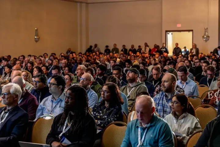 A ballroom audience many rows deep at All Things AI 2026, so full that the conference moves to a bigger venue in Raleigh for 2027