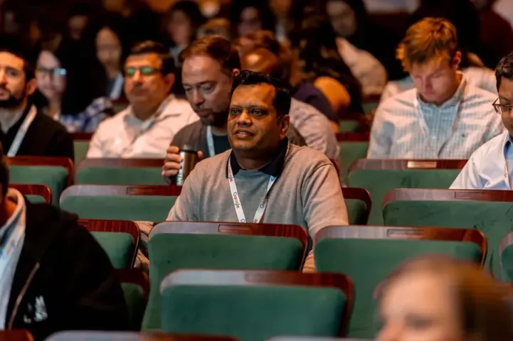An attendee in the Carolina Theatre's green seats smiling up at the stage, rows of listeners around him