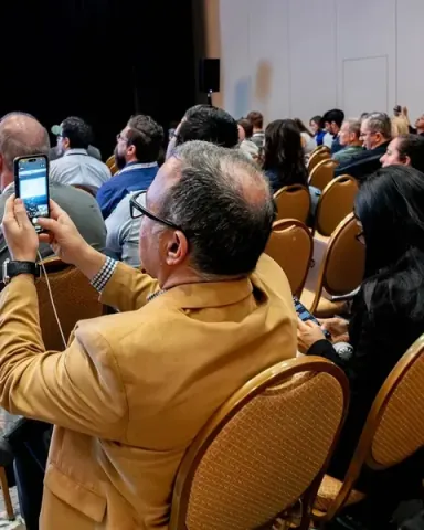 An attendee photographing a slide on his phone from the middle of a session