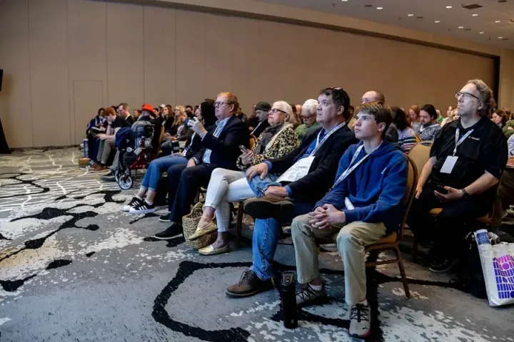 A full front row of attendees leaning in, all ages, at an All Things AI 2026 session