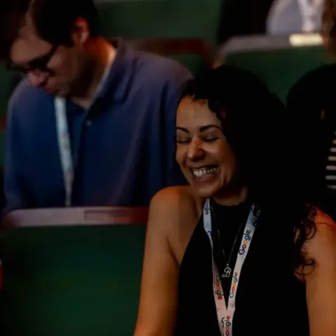 An attendee in a Google lanyard laughing in her Carolina Theatre seat