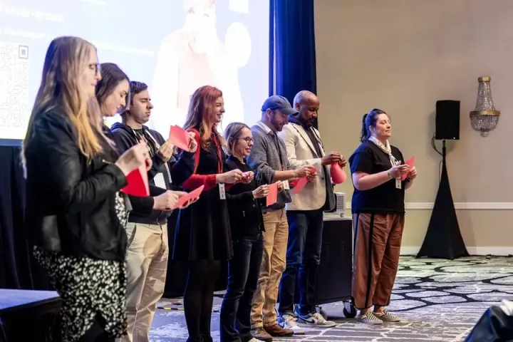 A line of presenters on stage, each holding notes, waiting their turn