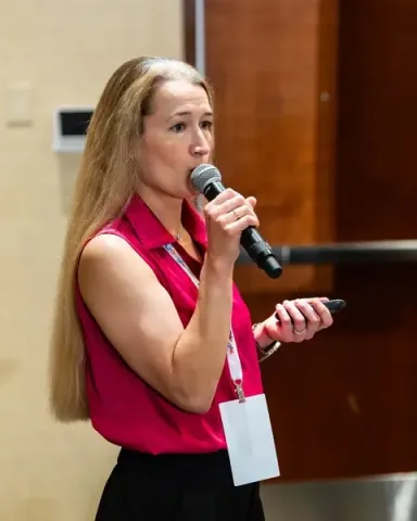 Anya Derbakova, Senior Solutions Architect at AWS, addressing the room with microphone and clicker in hand
