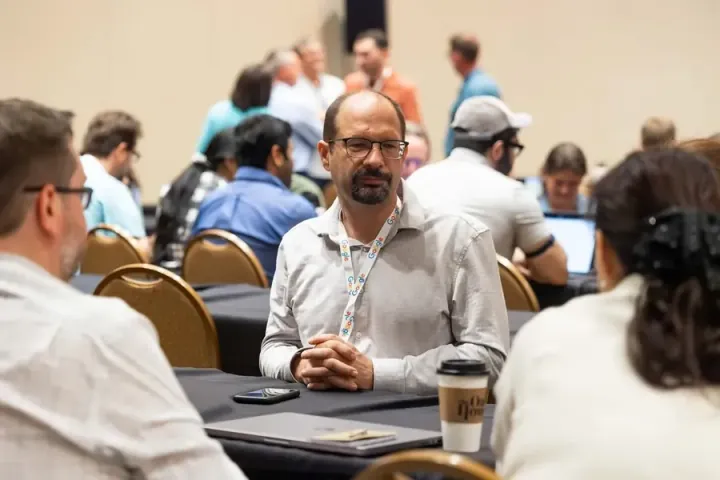 An attendee at a workshop table smiling across at the person next to him