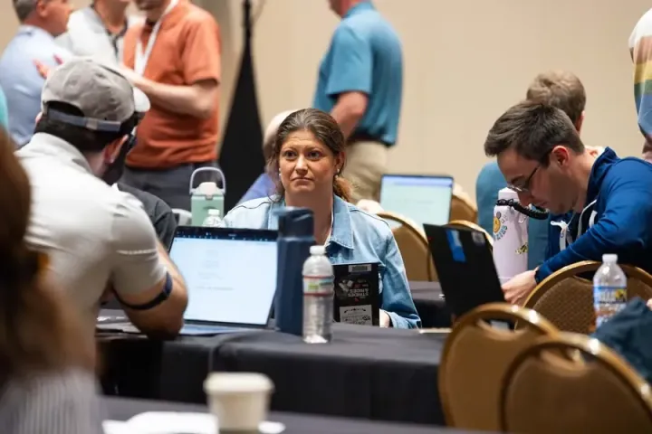 Workshop attendees around a table with laptops open, working an exercise together