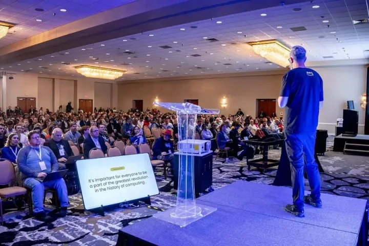 whurley on the keynote stage facing a full ballroom, his slide on a floor monitor