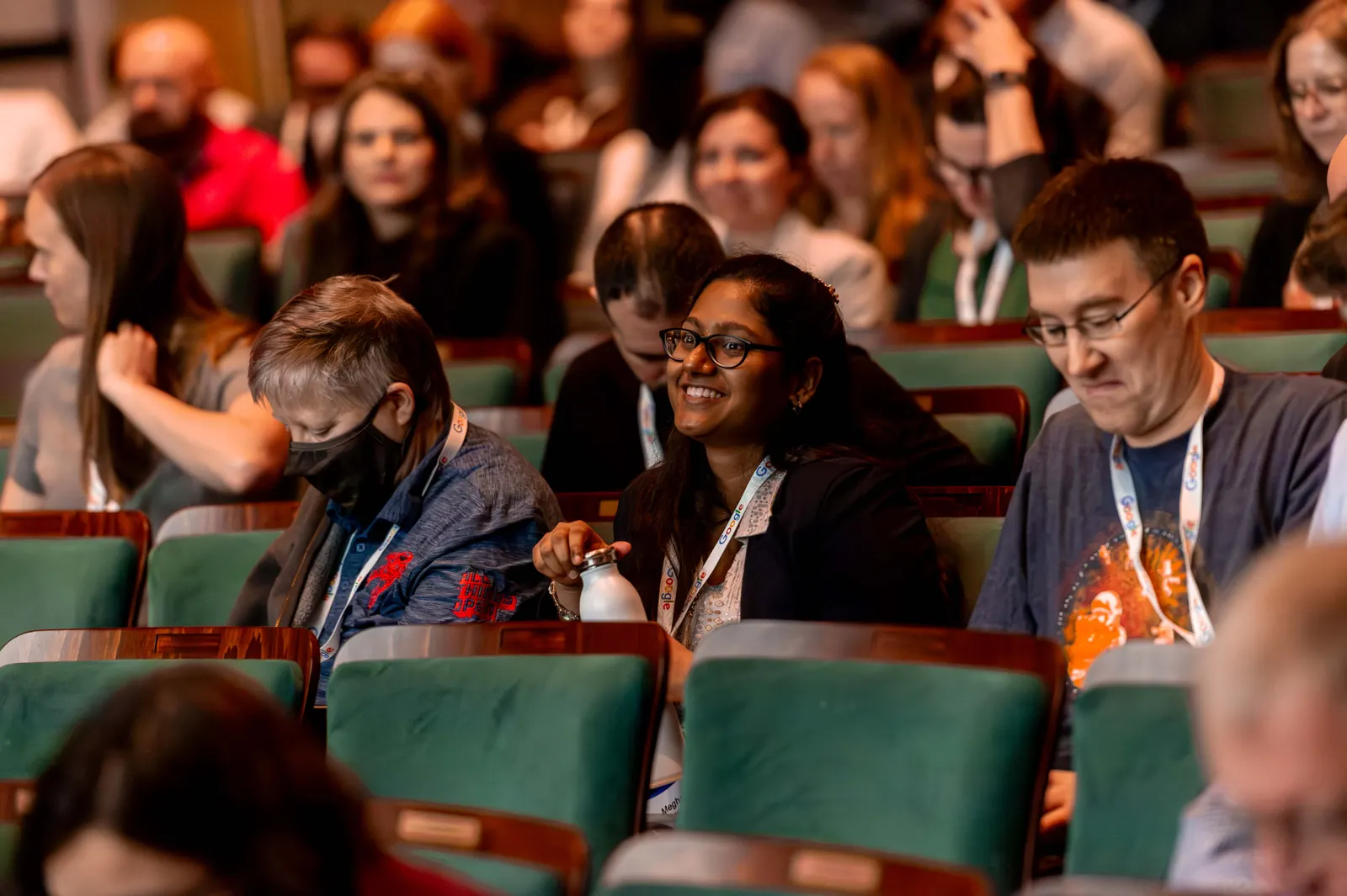 A smiling attendee among rows of listeners at the Carolina Theatre during All Things AI 2026