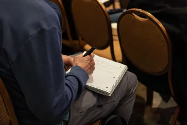 Close-up of an attendee taking handwritten notes during All Things AI 2026