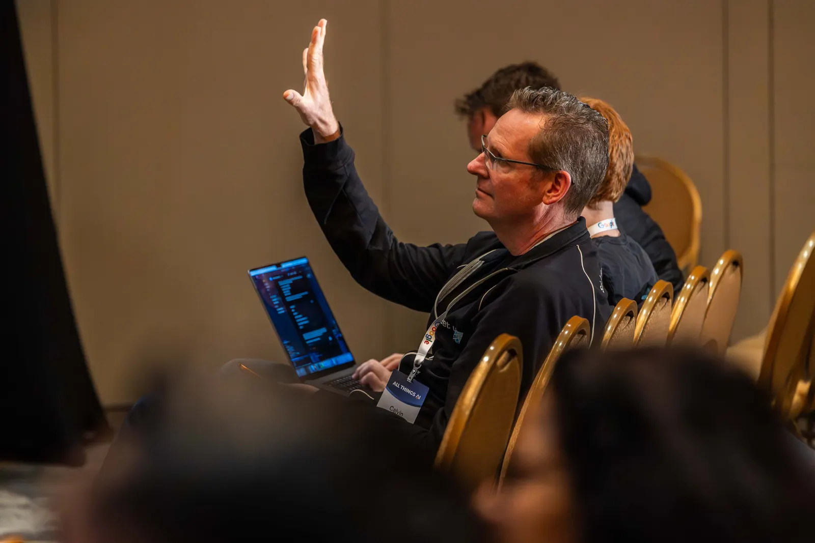 An attendee raising a hand from a seat during an All Things AI 2026 session