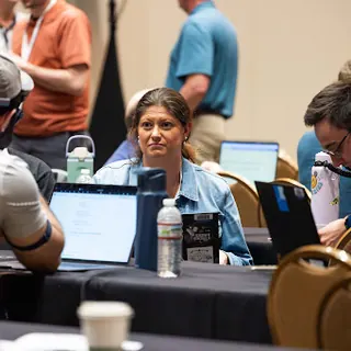 Two people at a workshop table looking up from their laptops